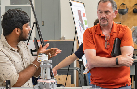 Two men talking while looking at a piece of research eqipment.