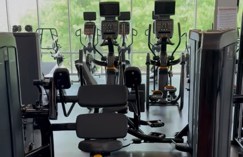 A weight machine with ellipticals in the background
