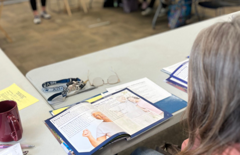 a woman is looking at a book in a classroom.