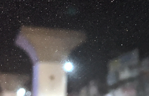 Blurred photograph at night. A light is shining and dust covers the lens.