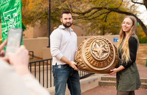 Photo of students holding large UNT class ring replica. 