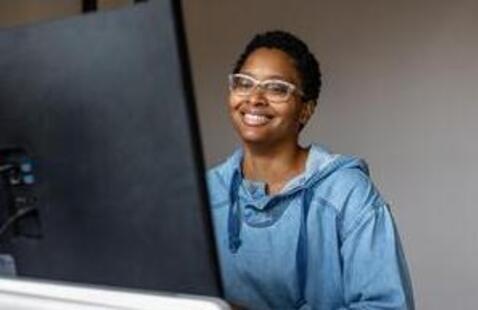 A woman sits at a computer screen.