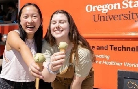 Two smiling students holding ice cream in front of Oregon State University ice cream truck.
