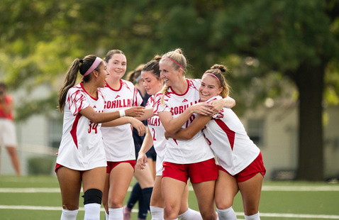 Members of the women's soccer team embrace on the field 