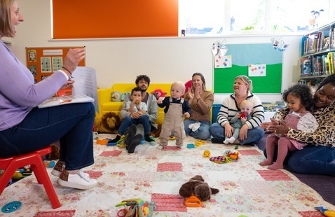 Children and caregivers sing with librarian at storytime