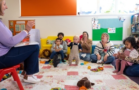 Children and caregivers sing with librarian at storytime