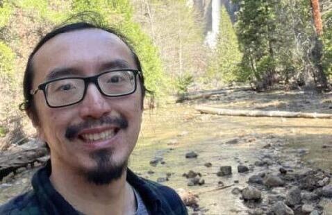 Jun Cai smiling by a creek