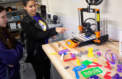 Students observing a 3D printer.