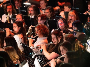 Orchestra flutists and woodwind players seated on stage, musicians performing during a concert