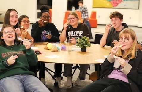 Six college students sitting at a table eating ice cream