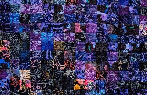 A close up of a purple and blue multicolored quilt