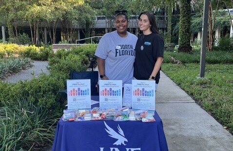 Two students standing at outside event table