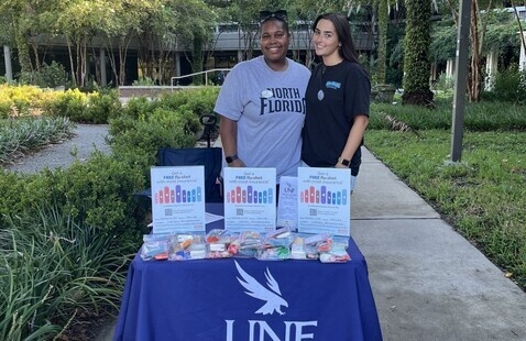 Two students standing at outside event table