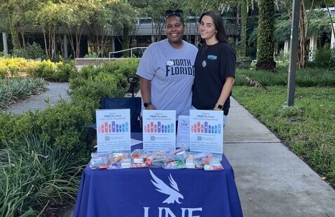Two students standing at outside event table