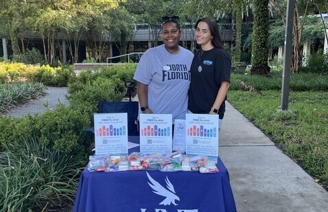 Two students standing at outside event table