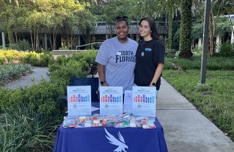 Two students standing at outside event table