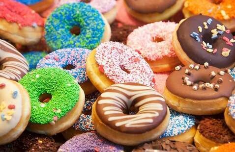 a pile of donuts with a variety of frosting and sprinkles