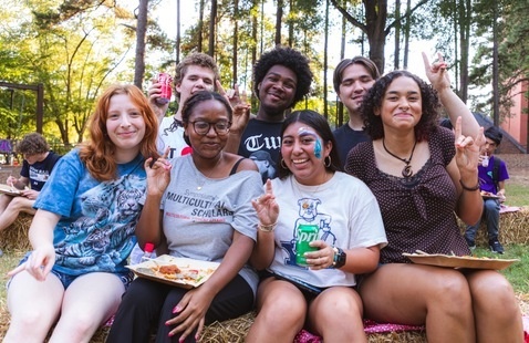 Students — some of them holding up the wolf sign — pose for a group picture.