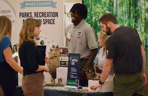 Staff at booth talking with attendees. 