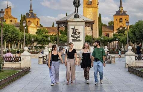 Four students walking through historic plaza in Alcalá de Henares Spain