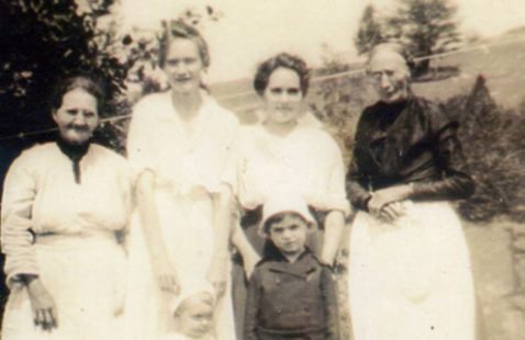 Black and white historic photo of four women and two little children.