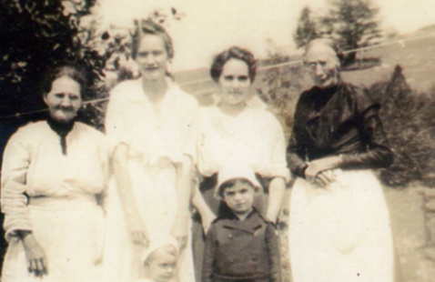 .Black and white historic photo of four women and two little children.