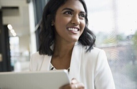 Professionally dressed woman smiling with tablet.