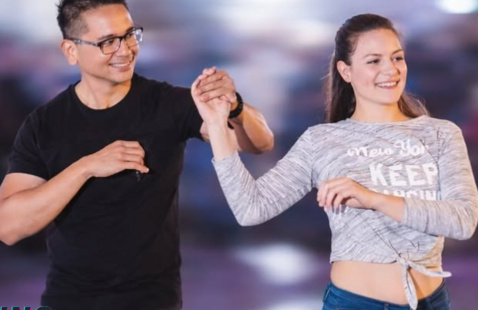 Lucky and Mae smile while dancing together, holding hands 