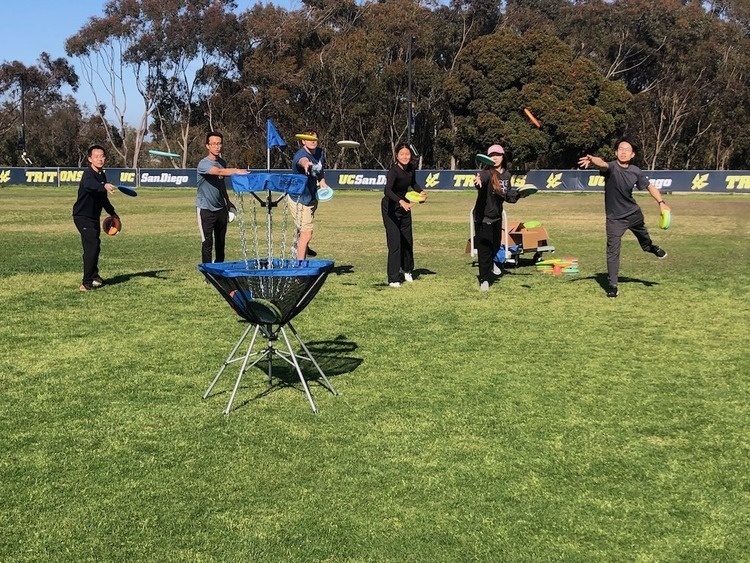A group of students in disc golf class throw into the target basket.