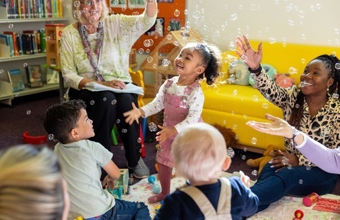 Children and caregivers playing with bubbles at storytime.