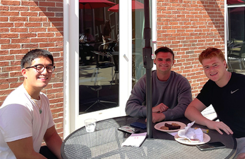 Three students at a courtyard table.