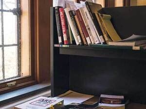 Library carrel overflowing with books next to a window.