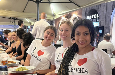 Students studying abroad in Perugia, Italy, pose for a picture as they sit in front of a table.