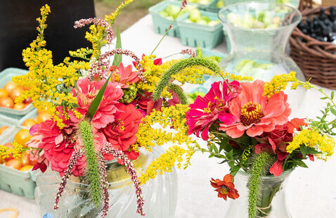Local flowers on a market table, with pints of cherry tomatoes in the background. 