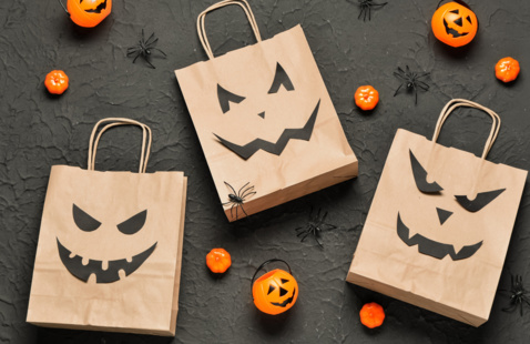 Halloween paper bags and small plastic pumpkins decorated with jack-o-lanterns faces