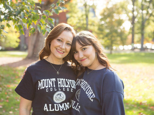 Two people pose together wearing Mount Holyoke College gear.