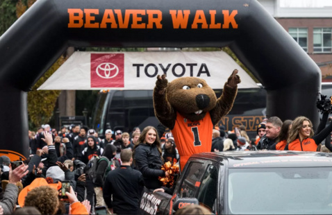 Benny and cheer squad under a black and orange inflatable arch.