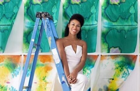 Maya Freelon standing on a ladder in front of colorful tissue paper