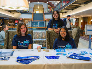Smiling orientation leaders sit at a table with MHC swag.