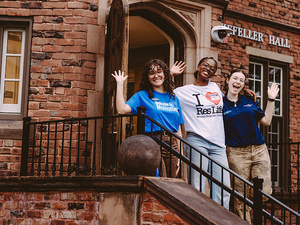 Smiling staff and Orientation leaders greet first year students on steps of Rockefeller Hall.
