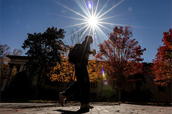 Student silhouetted against the sun on campus.