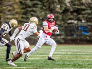 Colgate Football player running with football being chased by opposing team players