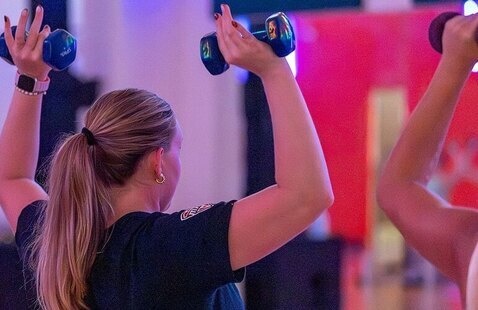 A person lifting two hand weights in front of a mirror.