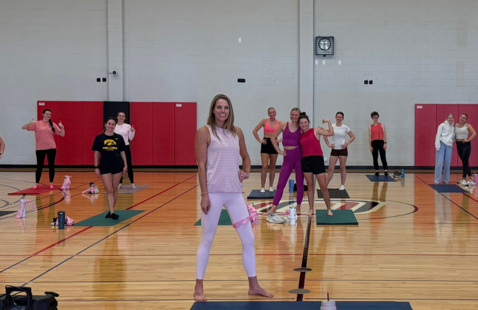 People posing for photo with yoga mats, wearing pink shirts at a Power in Pink event.