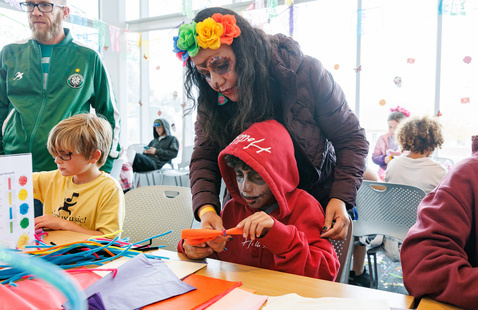 A parent and child creating flowers out of tissue paper