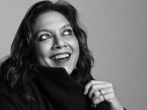 Mira Nair is shown in a black and white photograph smiling and looking up to the right.