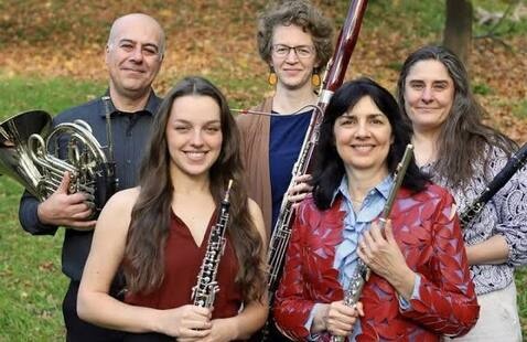 The five members of the quartet smile and hold their instruments 