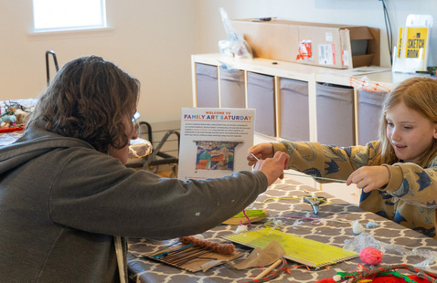A woman and a young girl work on an art project together