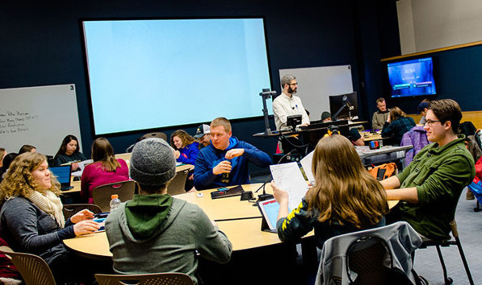 Students in a classroom with large round tables.