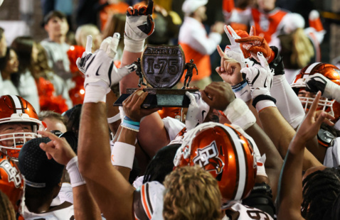 The bgsu football team in white jerseys during a game holding a trophie